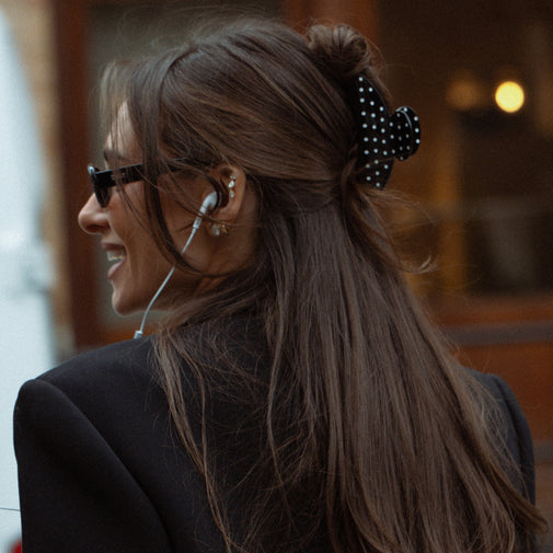 Woman with long hair tied back wearing glasses and a black blazer.