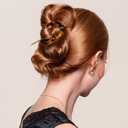 A woman wearing the Editorial Hoop & Pin Tortoise Barrette in a twisted bun