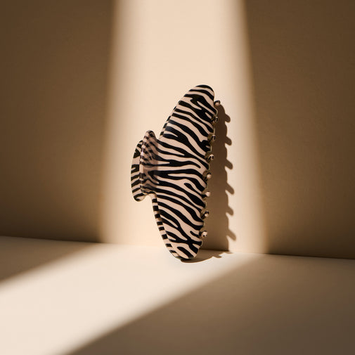 The Hair Edit Untamed Claw Clip standing up against a beige wall