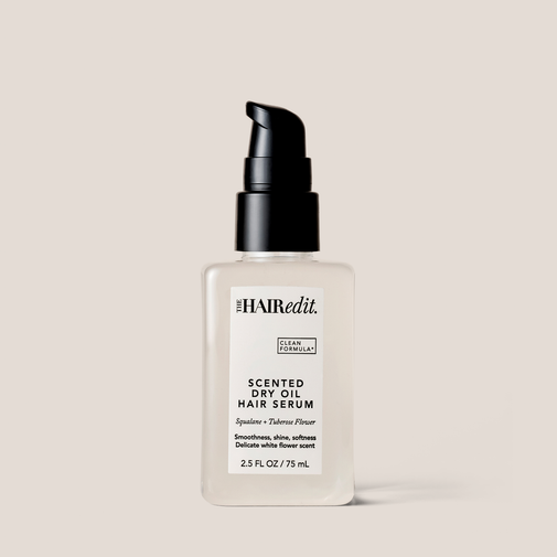 The Hair Edit Scented Dry Oil Hair Serum in a frosted glass bottle with a black pump dispenser, set against a solid light beige background.