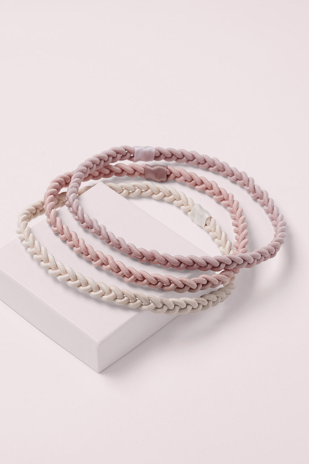 Salutation Slim Braided Headbands on a pink box 