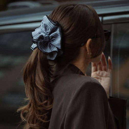 Person with a checkered hair accessory and sunglasses, blurred background