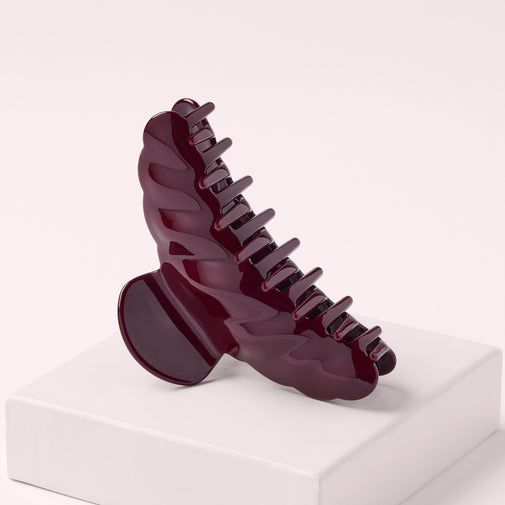 The Hair Edit Bordeaux Claw Clip on a pink box with a pink background