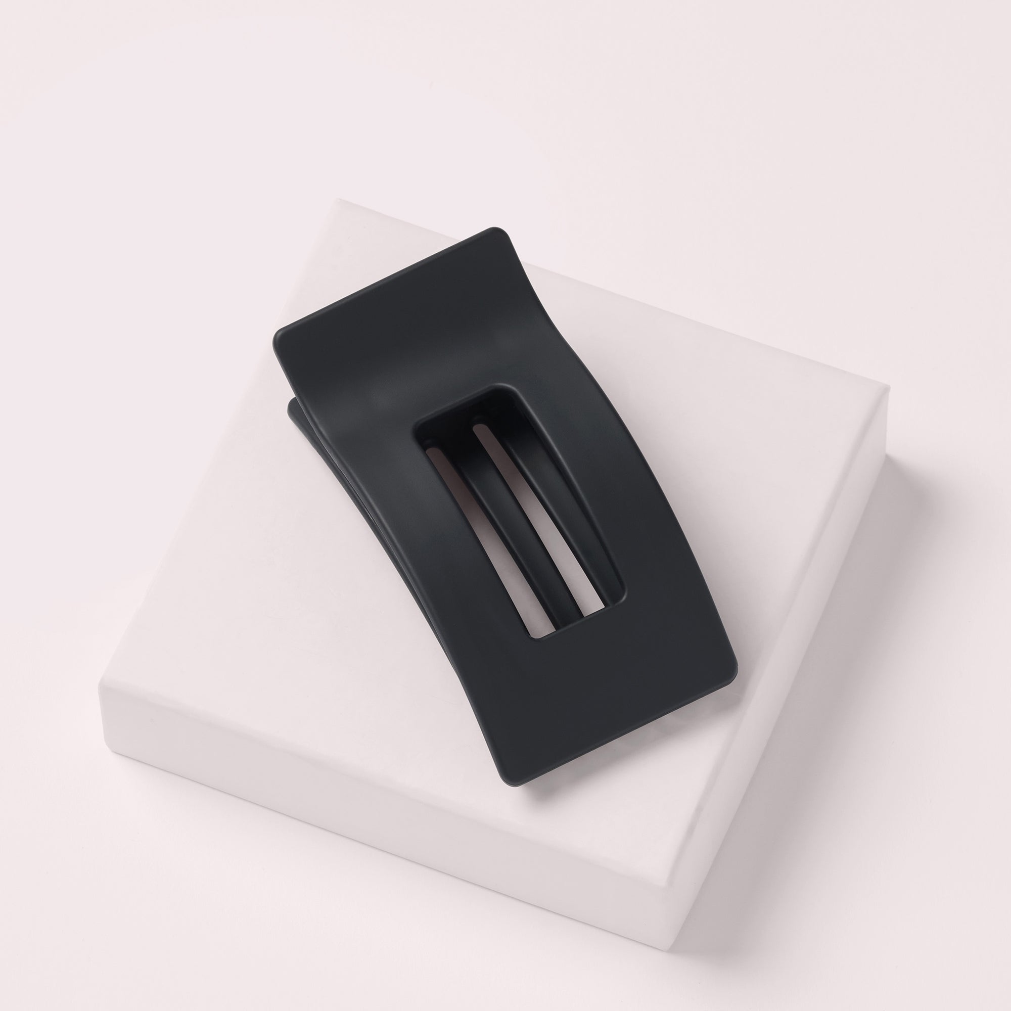 The Hair Edit Flexi Soft Flat Lay Claw Clip leaning on a pink box with a light pink background5