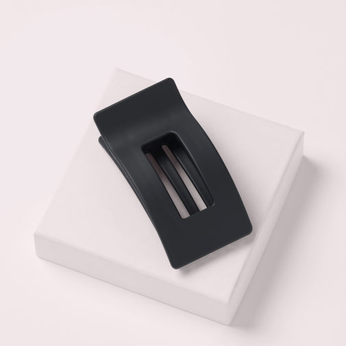 The Hair Edit Flexi Soft Flat Lay Claw Clip leaning on a pink box with a light pink background