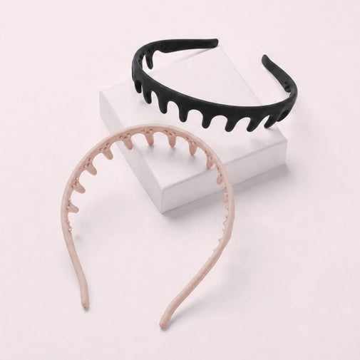 Two silicone zig zag hair headbands with a dripping or wavy edge design, one in black and one in light pink, displayed on a pink box with a pink background