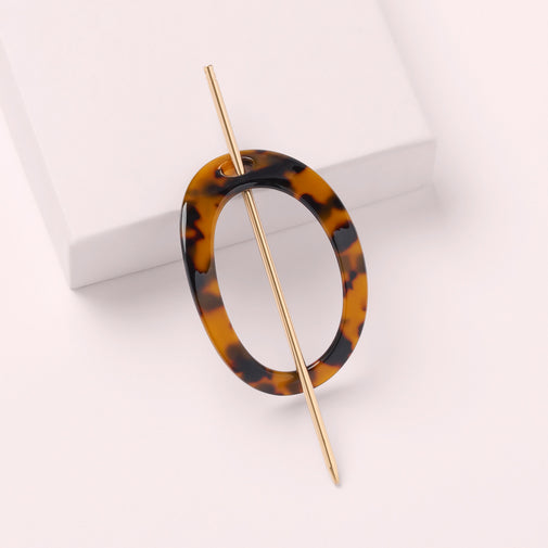 The Hair Edit Editorial Hoop & Pin Tortoise Barrette on a pink box with a pink background