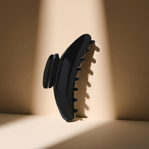 The Hair Edit Midnight Claw Clip standing up against a beige wall