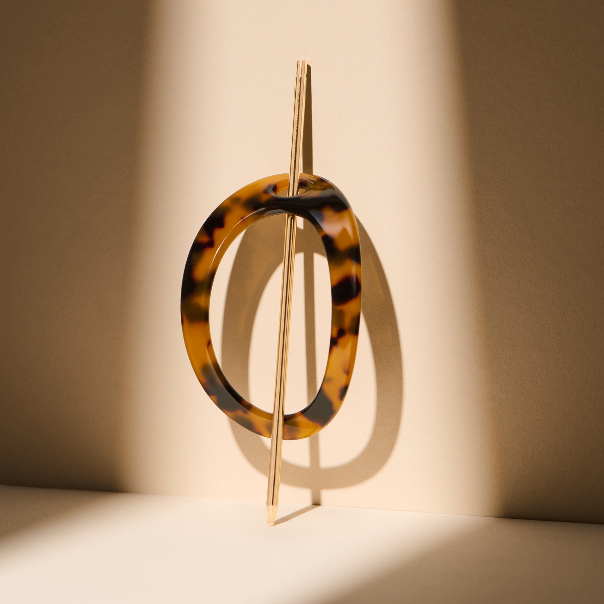The Hair Edit Editorial Hoop & Pin Tortoise Barrette standing up against a beige wall6