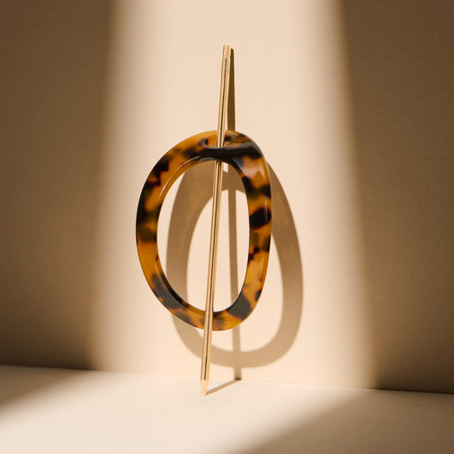 The Hair Edit Editorial Hoop & Pin Tortoise Barrette standing up against a beige wall