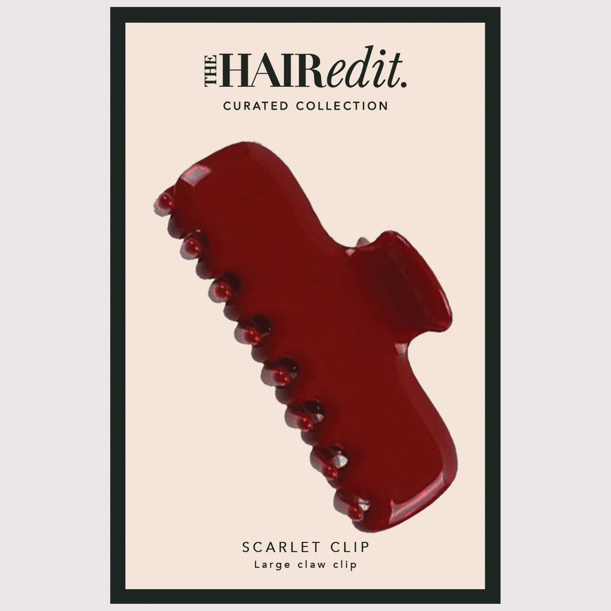 A glossy scarlet red claw clip displayed on a cream-colored product card with black text reading 'The Hair Edit. CURATED COLLECTION' and 'SCARLET CLIP Large claw clip'.6