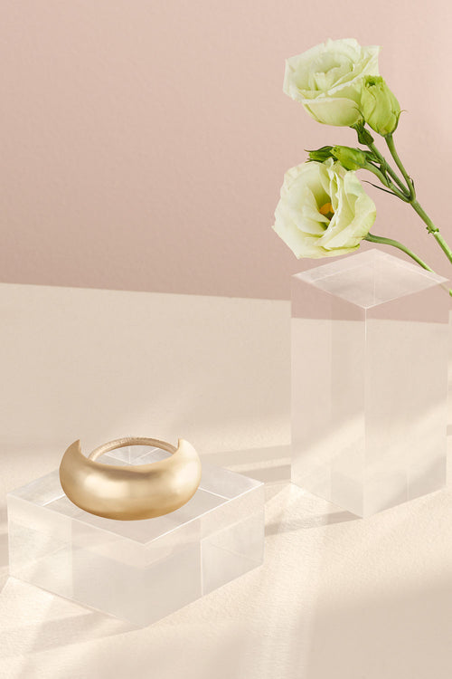 The Hair Edit Brilliant Cuff Arched Gold Metal Hair Tie in a lifestyle setting with flowers 
