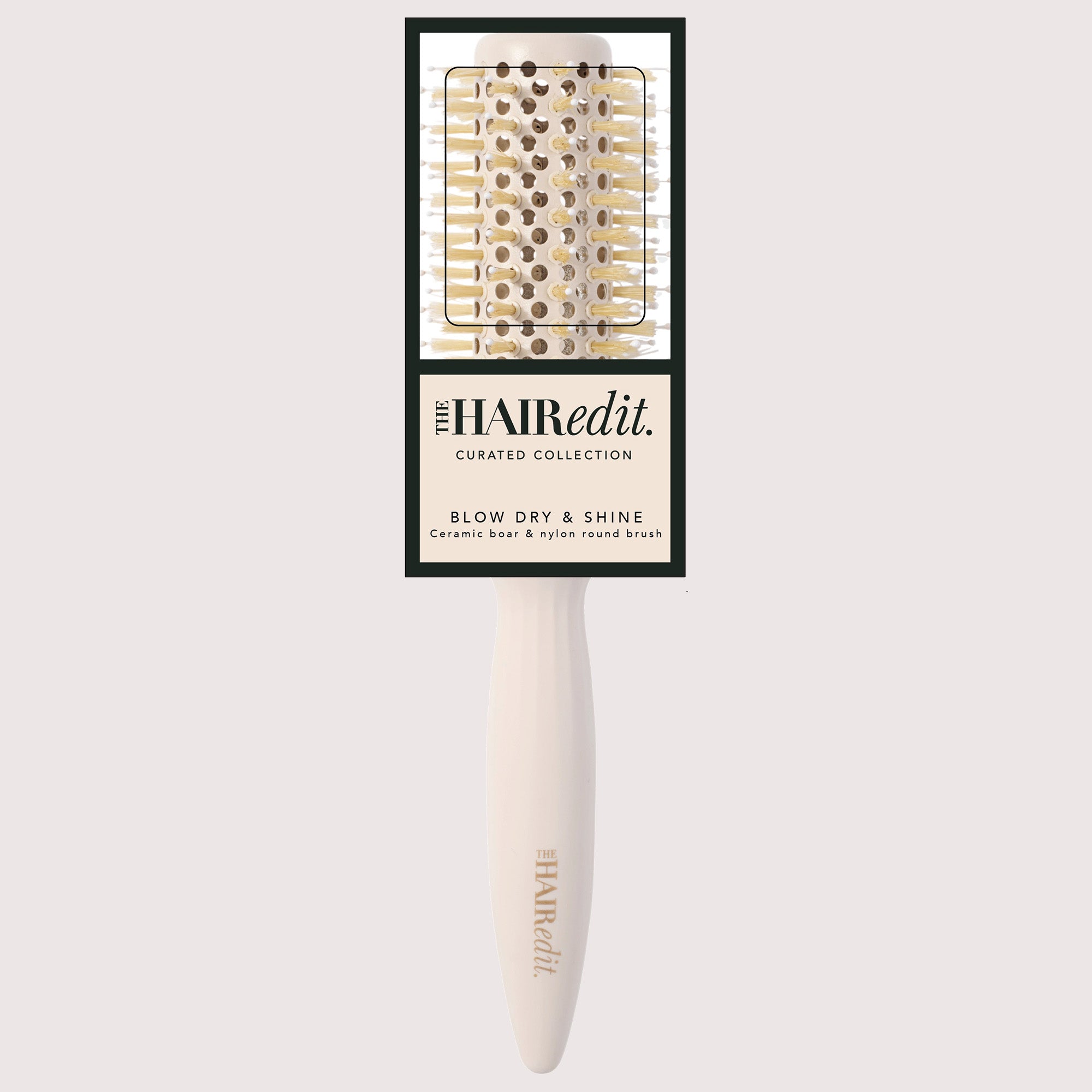 The Hair Edit Blow Dry & Shine ceramic brush with a cream-colored handle and gold-toned bristles, shown with its original black and cream packaging card against a light gray background.7