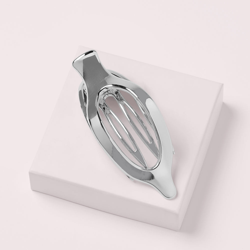 A polished silver metal hair claw clip displayed on a a pink box with a light pink background8