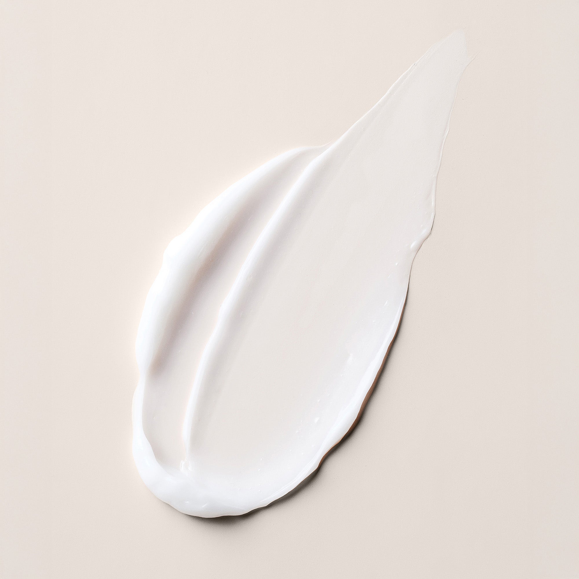 A thick, creamy white smear of Multi Benefit Leave-In Conditioner on a solid, warm beige background.8