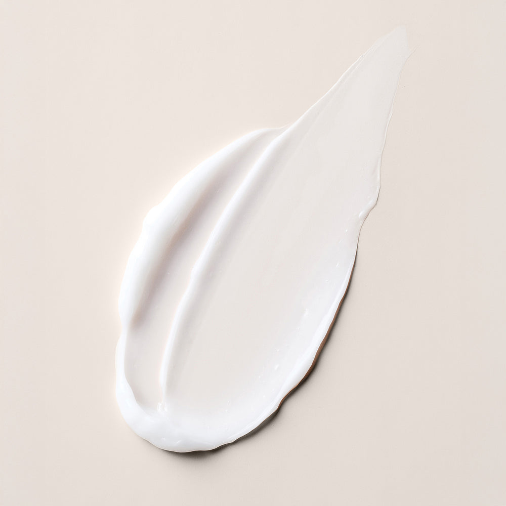 A thick, creamy white smear of Multi Benefit Leave-In Conditioner on a solid, warm beige background.8