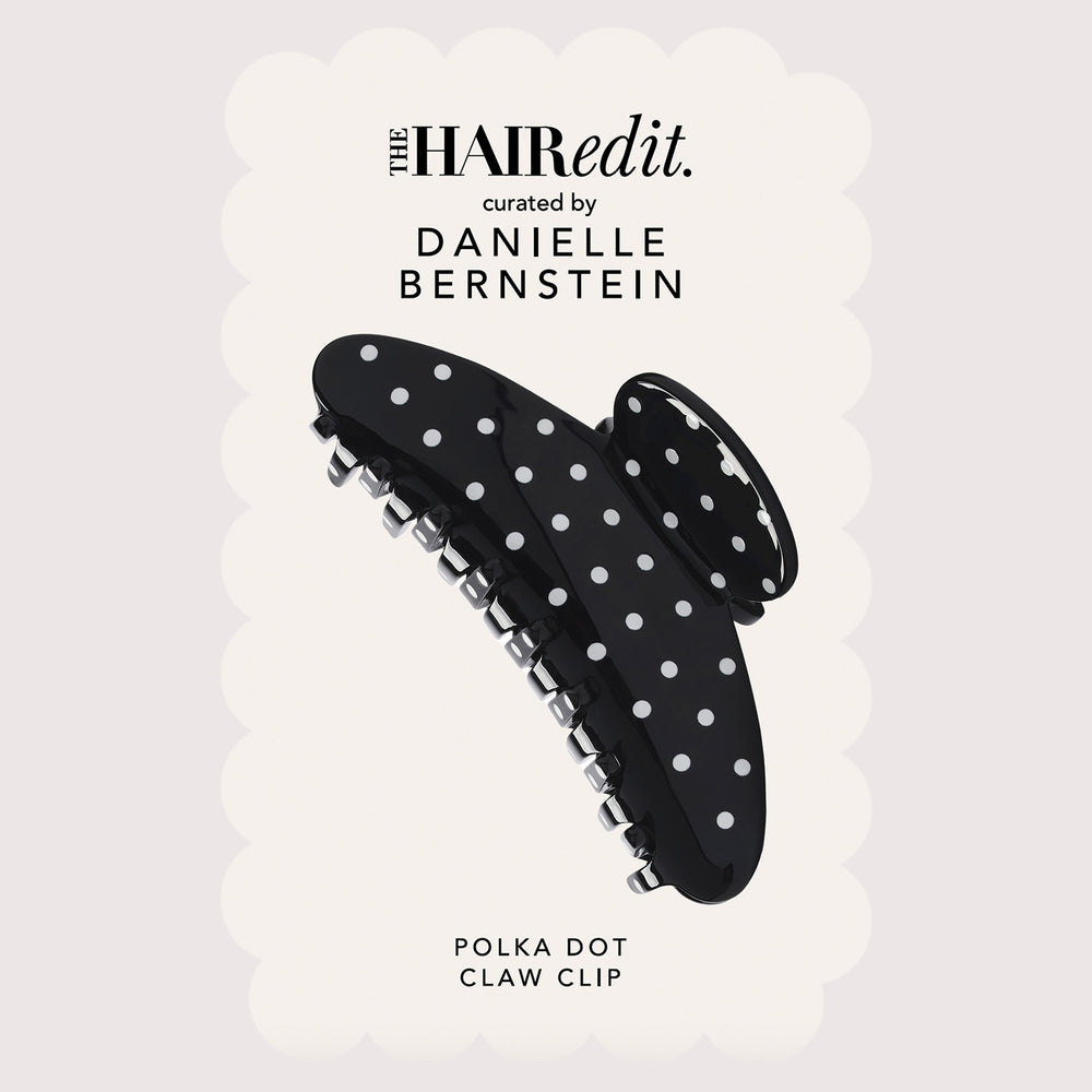 A black claw clip with white polka dots, shown against a light cream scalloped background with text reading 'the HAIRedit. curated by DANIELLE BERNSTEIN' and 'POLKA DOT CLAW CLIP'.10