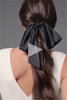 A video of a model putting Runway Ribbon Satin Hair Bow in her hair 