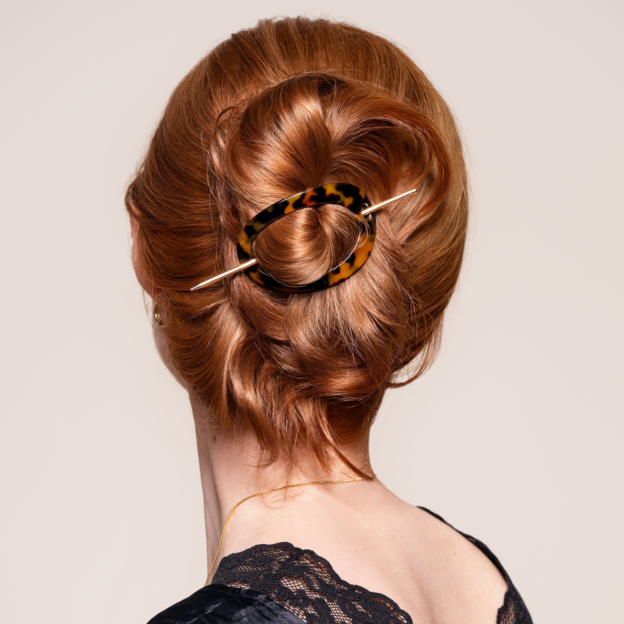 A woman wearing the Editorial Hoop & Pin Tortoise Barrette in a twisted bun3