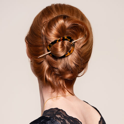 A woman wearing the Editorial Hoop & Pin Tortoise Barrette in a twisted bun