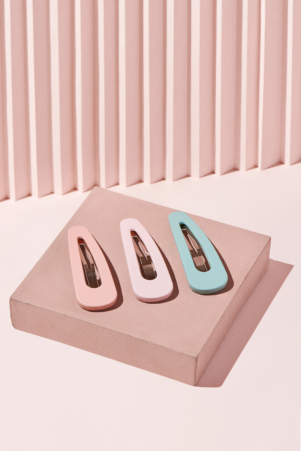 The Hair Edit Pastel Colored Matte Snap Triangles Hair Clip Accessories on pink display