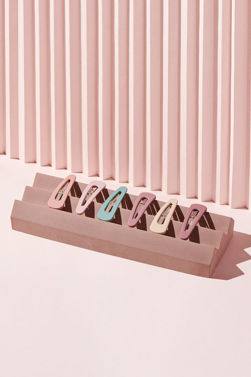 The Hair Edit Pastel Colored Matte Snap Triangles Hair Clip Accessories on pink display