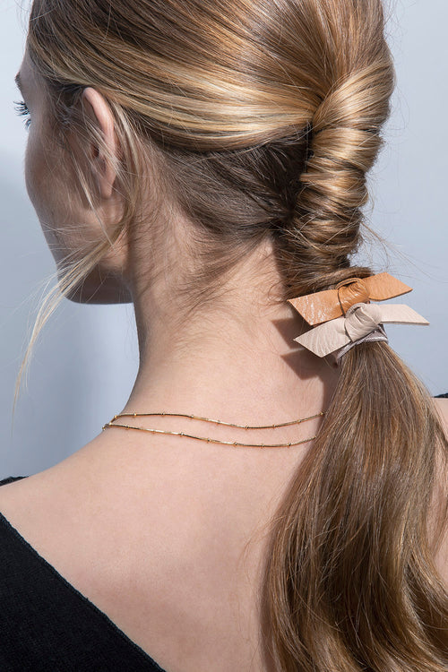 The Hair Edit Vegan Faux Leather Hair Tie Bow Accessories Set of 3 Ties in Beige & Brown Colors styled on twisted ponytail of blonde haired female model close-up