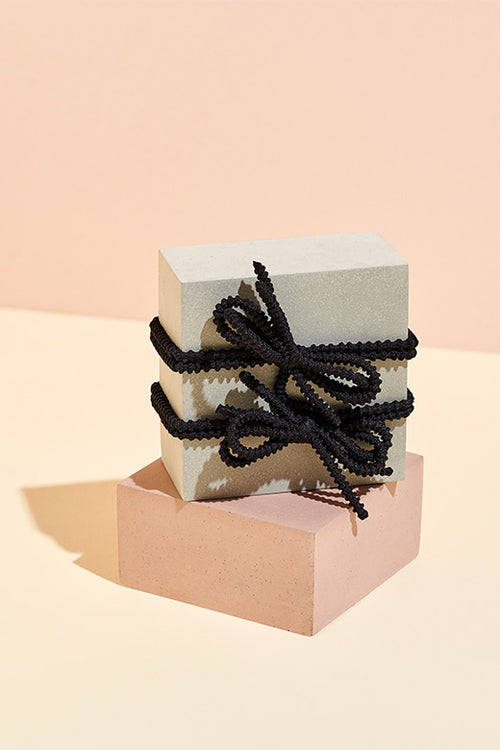 The Hair Edit Black Knotted Bow Hair Tie Set 2 Pack displayed with pink backdrop