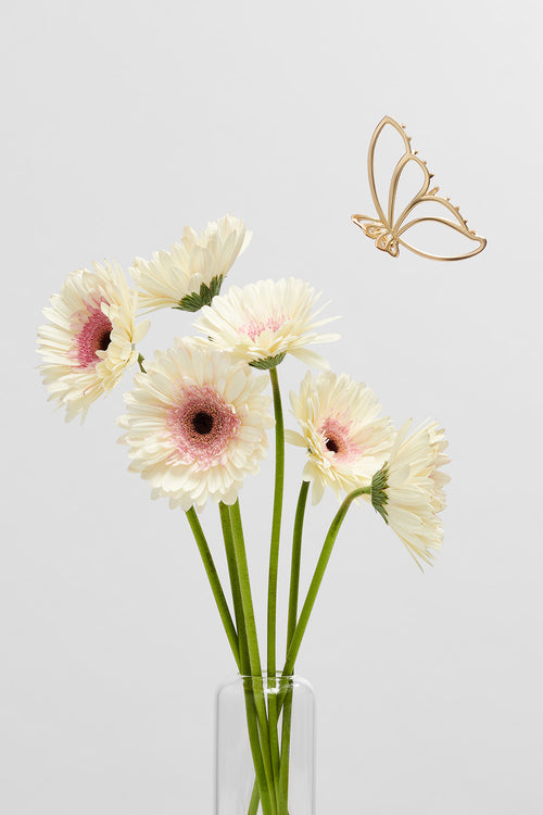 gilded wing gold metal butterfly hair claw clip floating above spring flowers