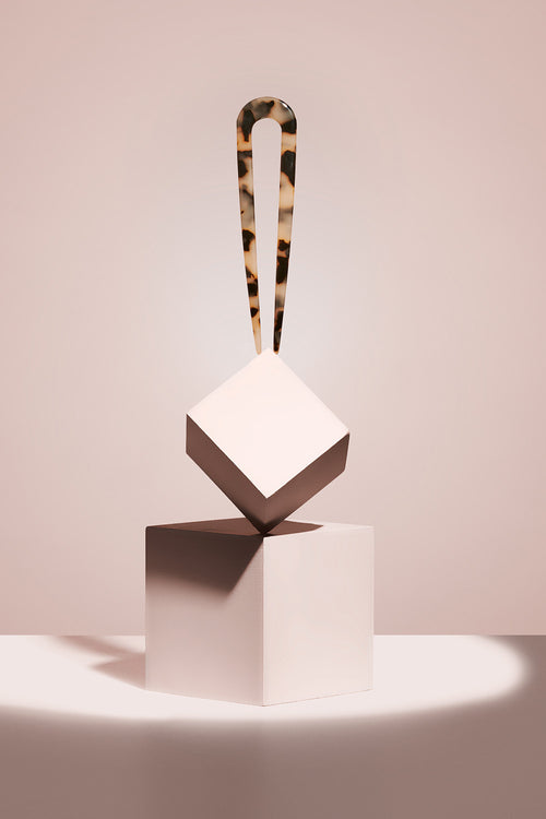 model with tortoise chignon u shaped pin presented on a cube